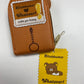 Original back photo of Rilakkuma Card Wallet showing the embroidered patch and yellow paper tag